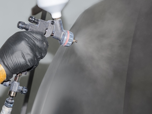 Painting of automobile parts, a man's hand with a spray gun,